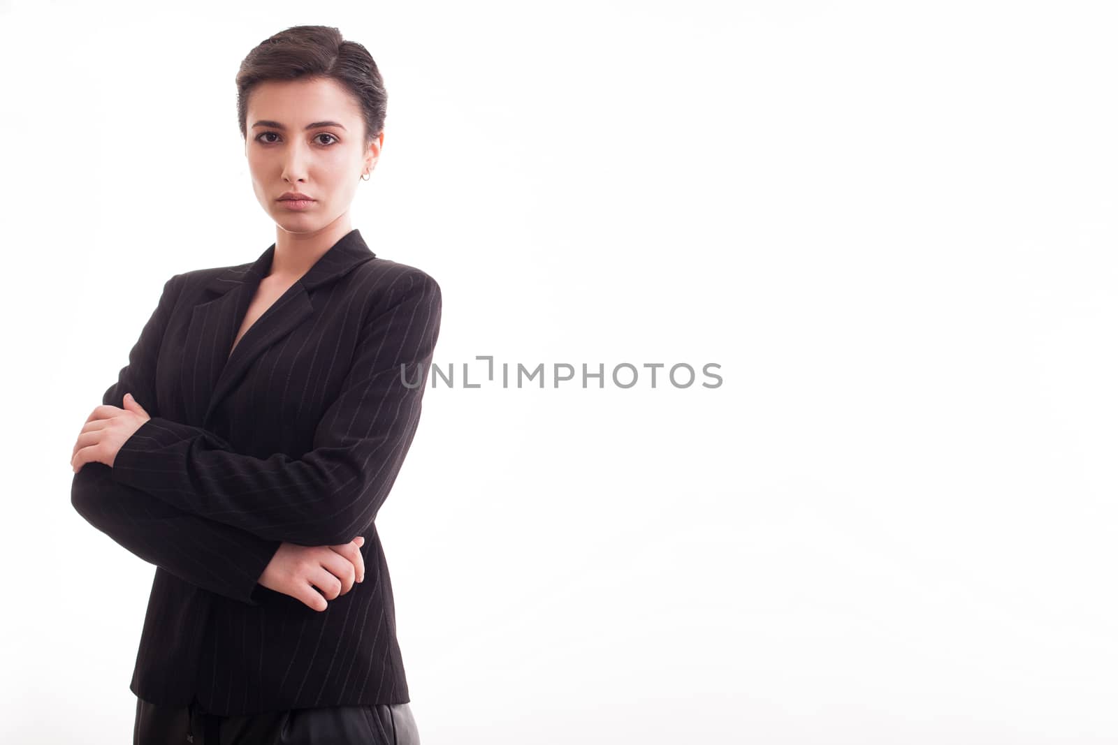 Beautiful and attractive young woman with hands crossed over white background wearing a black jacket. Copy space available.