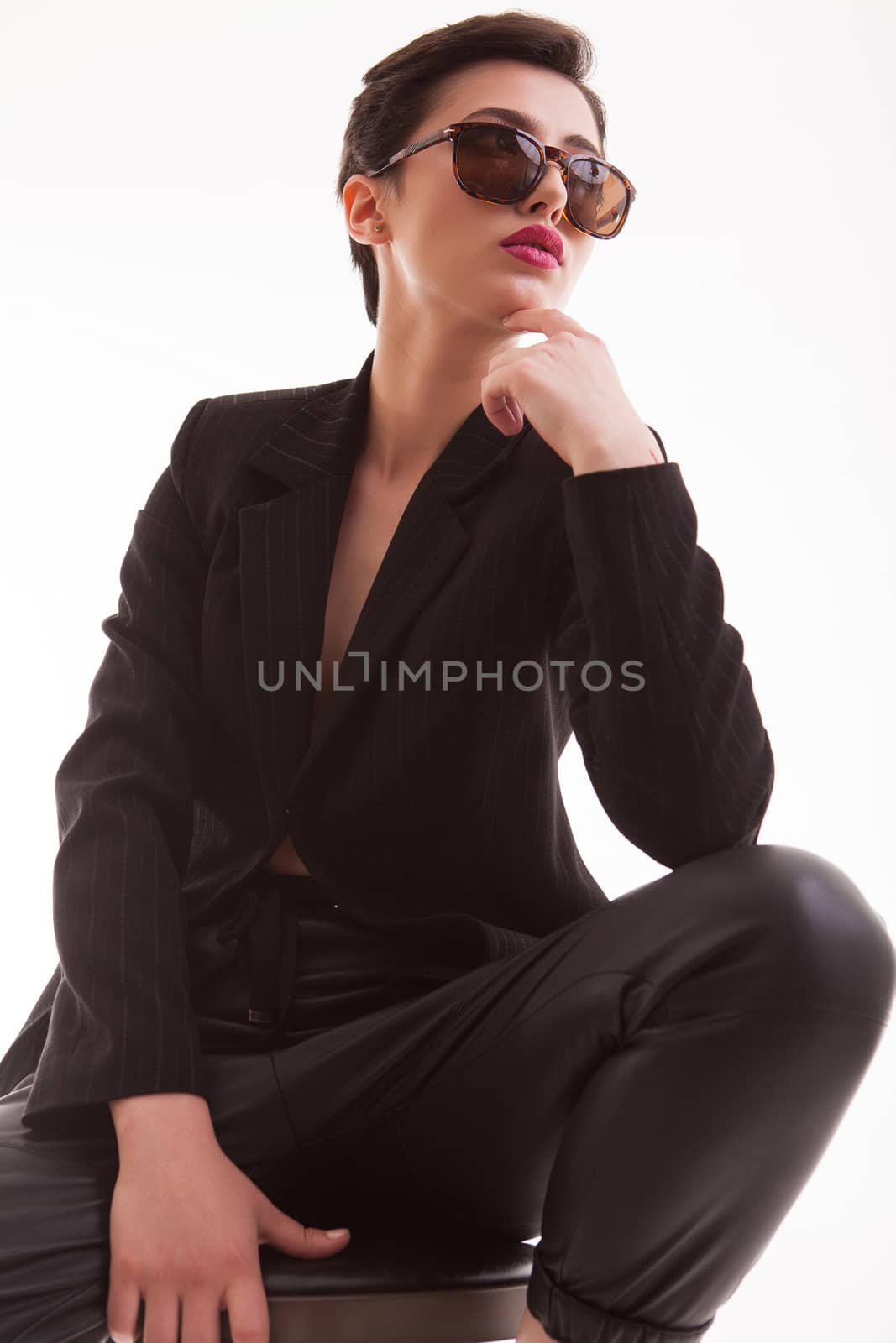 Beautiful young fashion model with sunglasses posing in studio over white background. Full body portrait. Posing with hands.