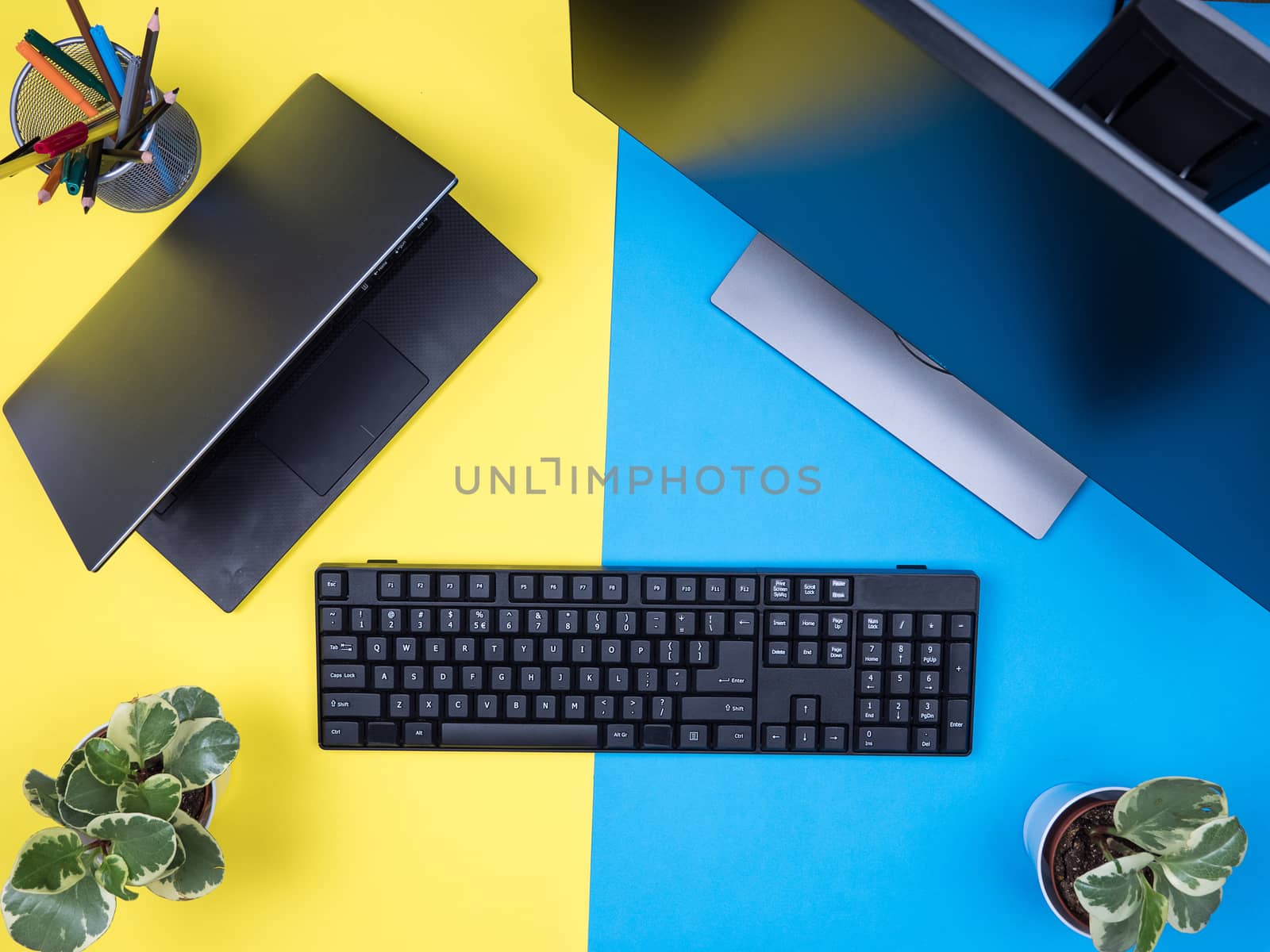 Flat lay top view of keyboard next to modern laptop over blue background. Workplace concept.