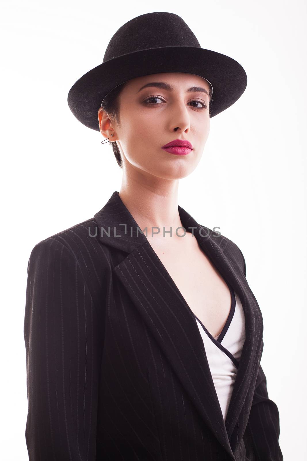 Portrait of young fashion model with a stylish hat posing in studio over white background. Black jacket.