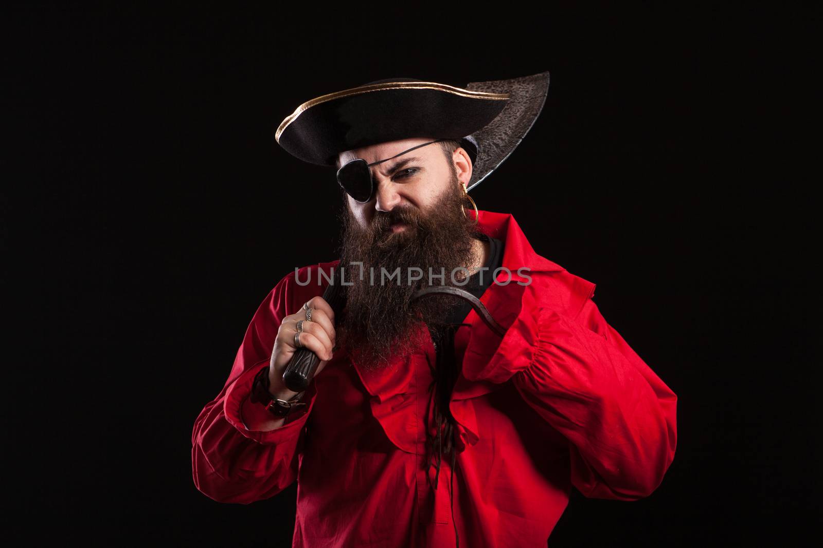 Angry man in a pirate capitan costume for halloween holding and axe on his shoulder. Handsome bearded man with a pirate hat.