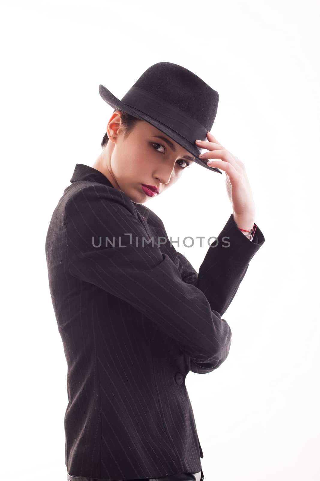 Glamorous female posing in studio wearing a black jacket with a stylish hat. Caucasian beauty.