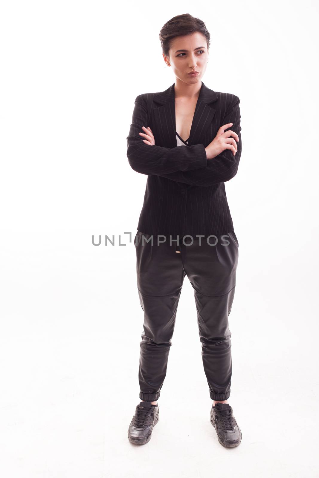 Full body portrait of fashion model with a serios face looking to her left wearing a black jacket over white background. Casual clothing.
