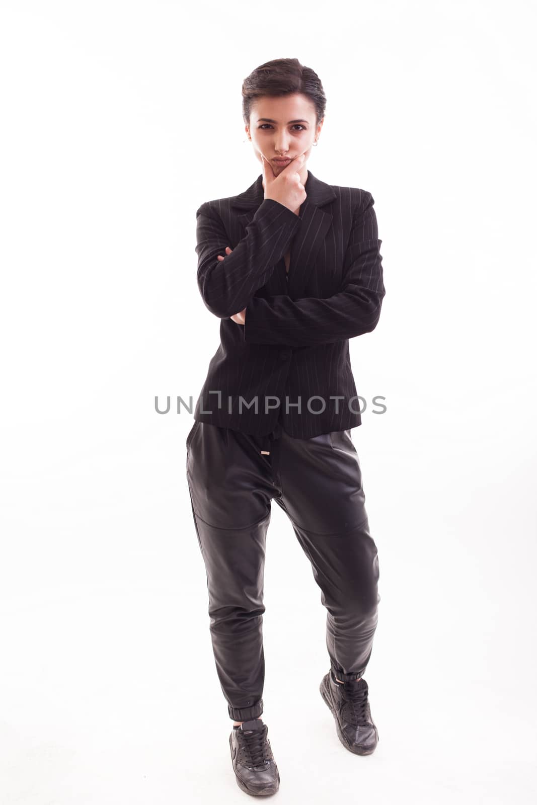 Beautiful young girl with hands crossed and serious face posing over white background. Casual black jacket.