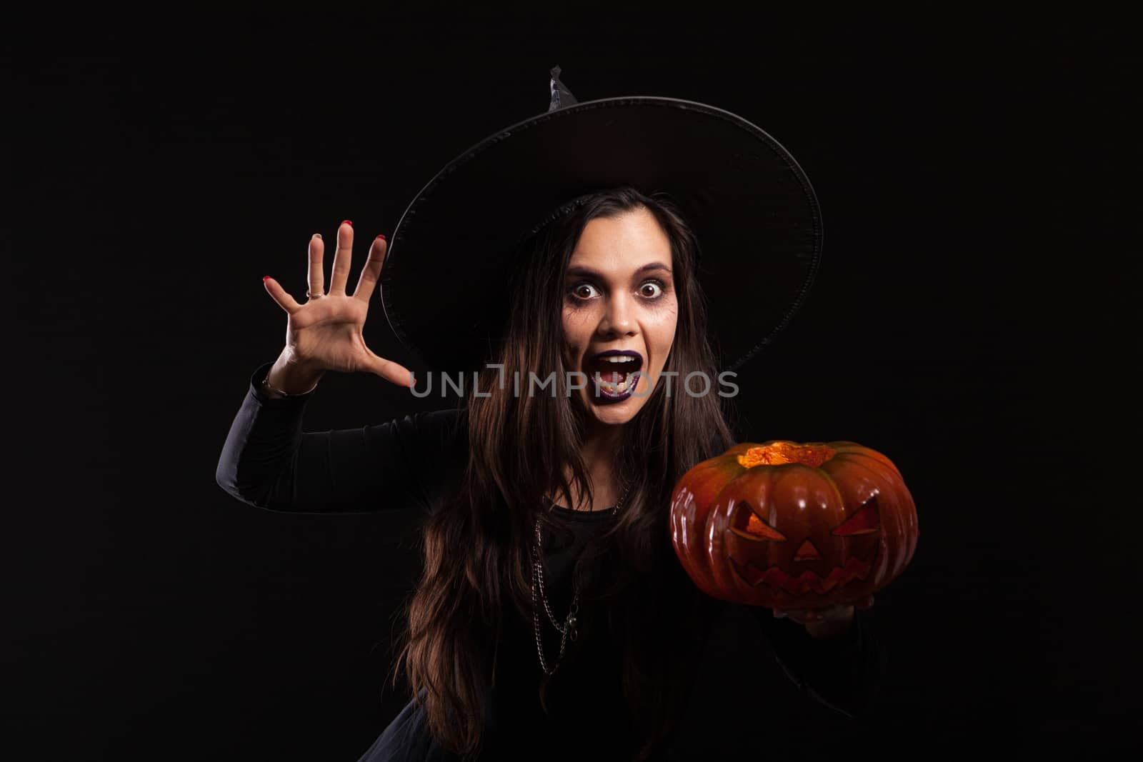 Caucasian young woman dressed up like a witch and screaming to the camera. Halloween dress. Scary lady on halloween.