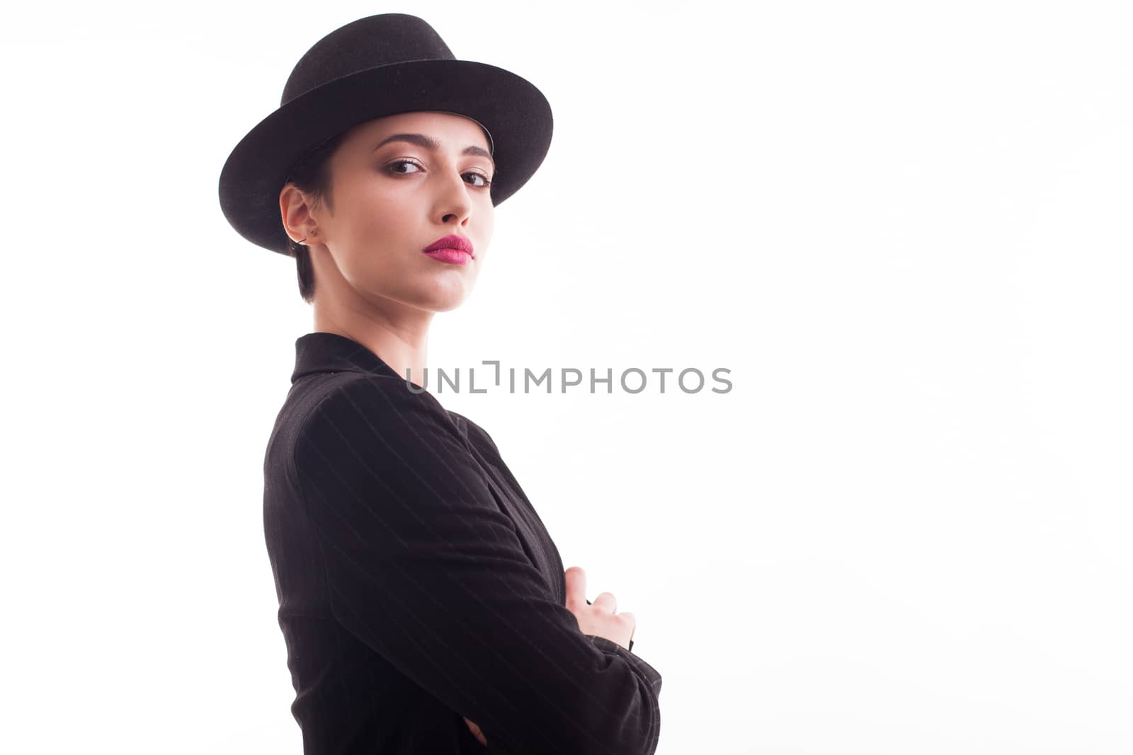 Confident fashion model with stylish black hat looking at the camera over white background in studio. Copy space available.