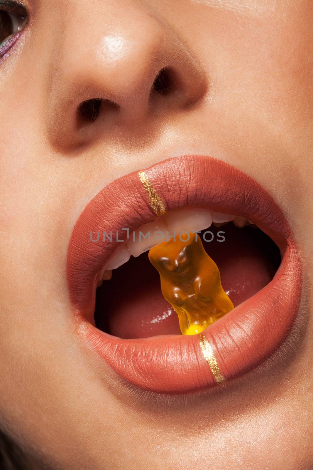 Close up view of beautiful woman lips with gummy bear. Concept shot. Studio shot. Beauty shot. Fashion shot.