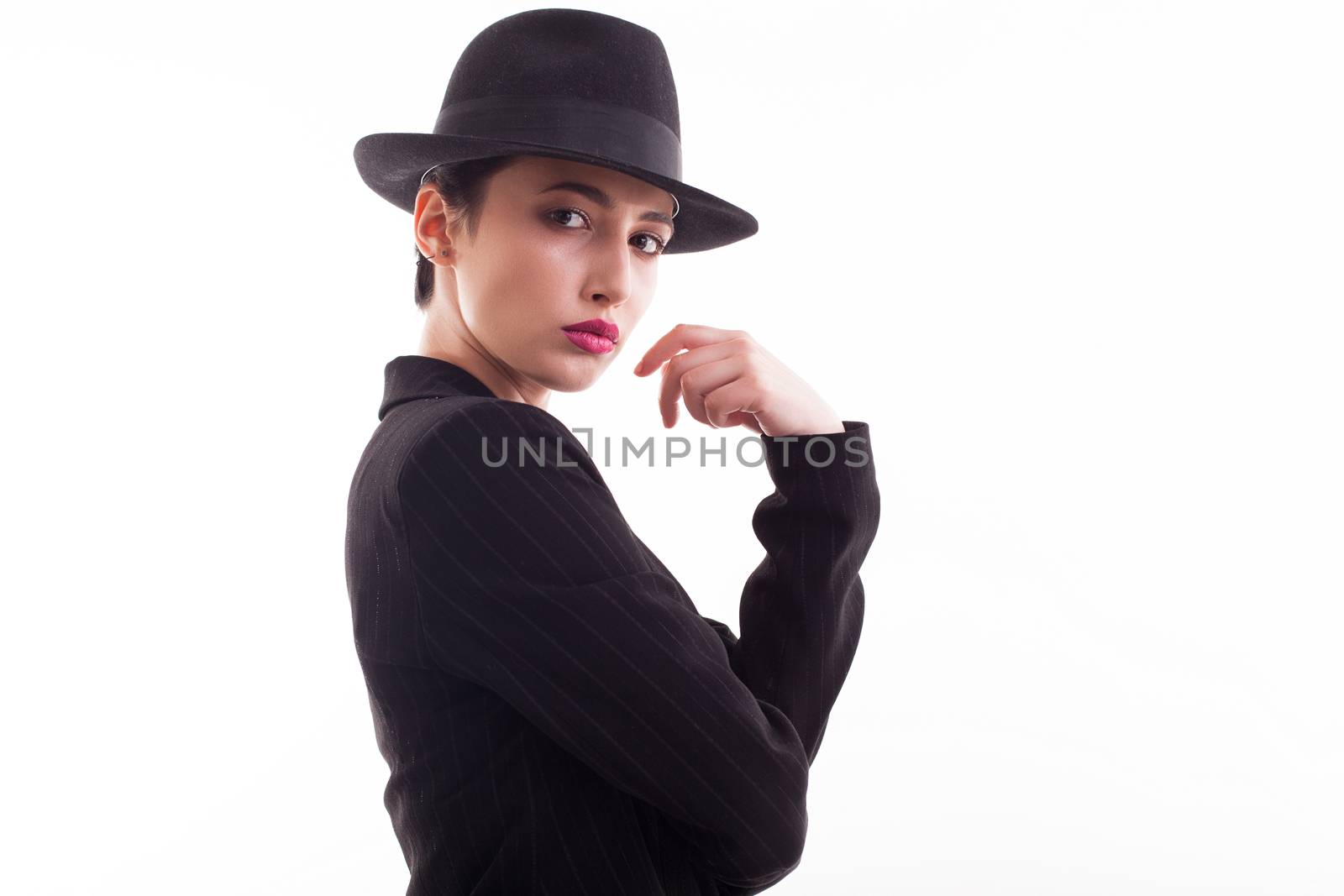 Fashion model posing looking at the camera wearing a retro hat over white background in studio. Fashion photography.