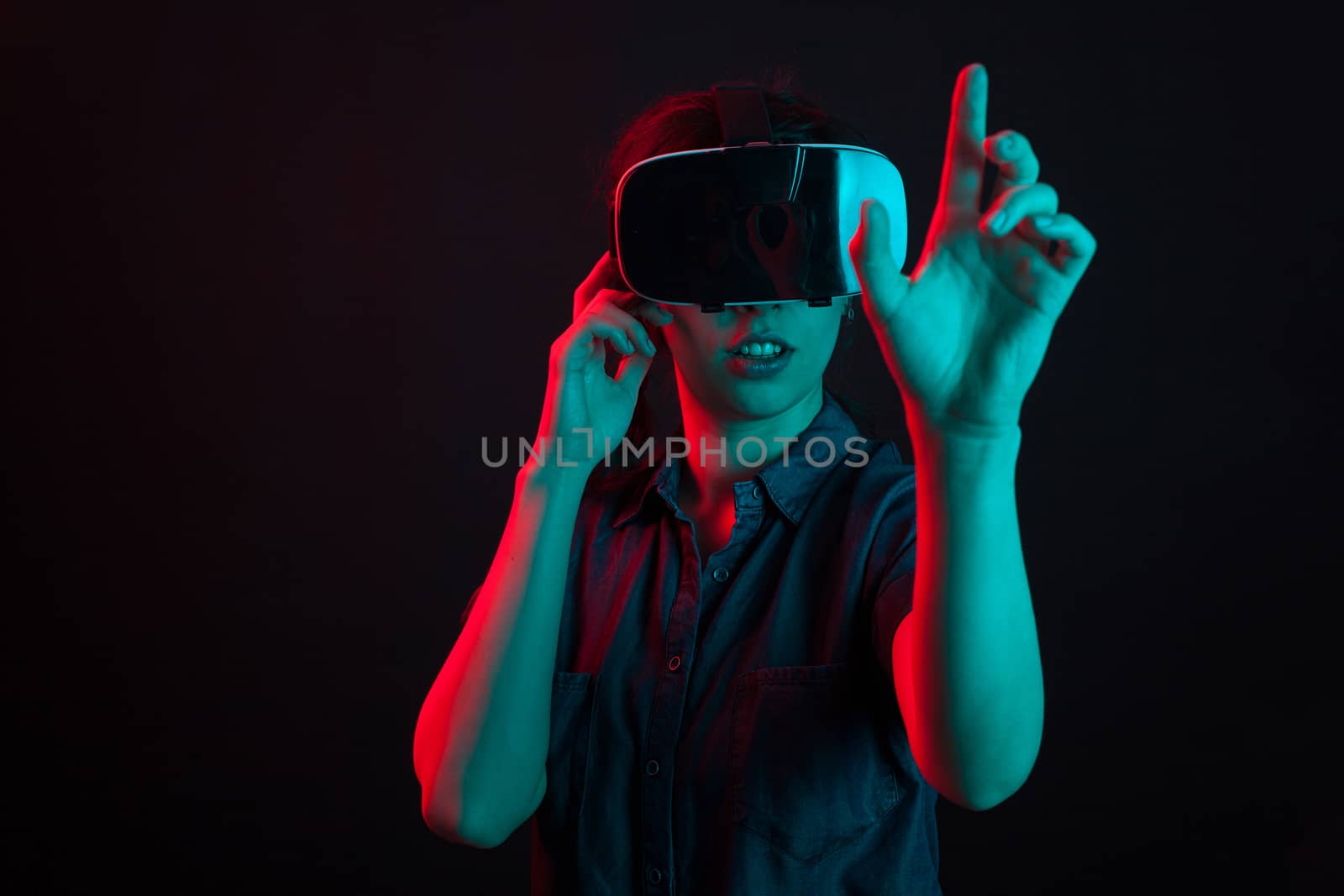 Attractive caucasian woman amazed in studio with virtual reality helmet. Modern device for games. Futuristic innovation experienced by young woman.