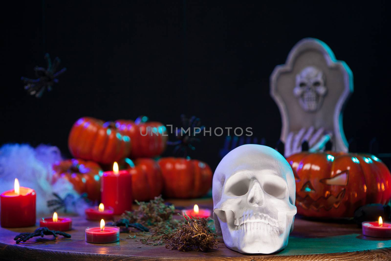 Spooky human skull with scary pumpkin behind on wooden table for halloween celebration. Halloween celebration.
