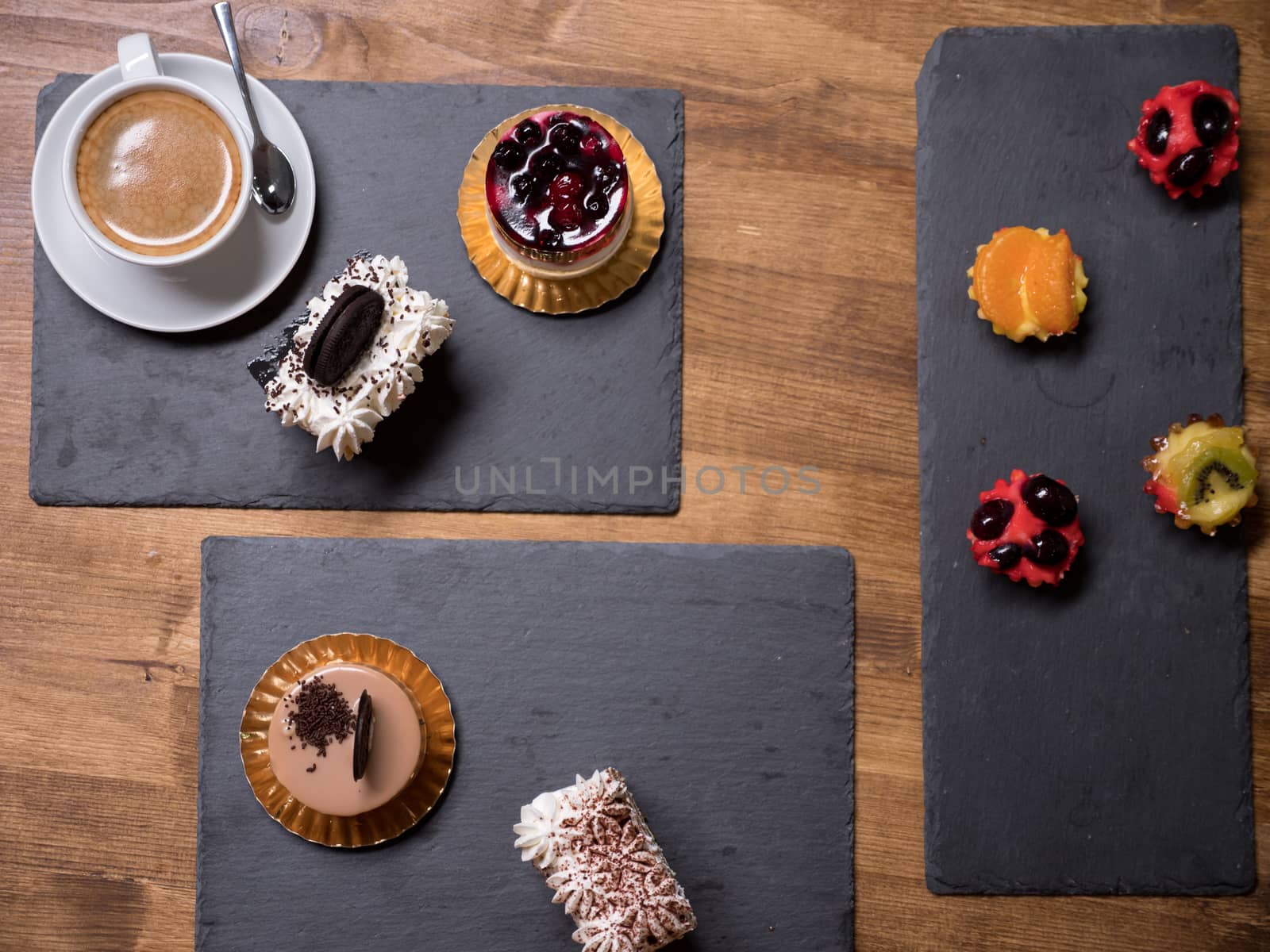 Top view of delicious cakes of different flavours and colors over wooden table. Tasty desserts. Fresh desserts. Delicious cup of coffee. Different pudding cake.
