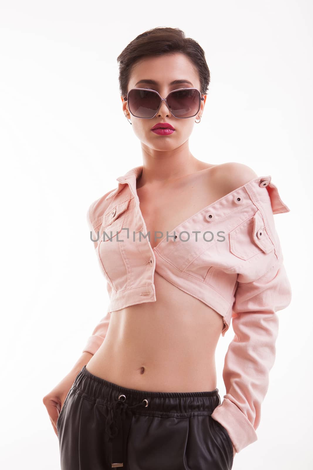 Stylish young female posing in studio wearing a pink jacket over white background. Girl with short hairstyle.