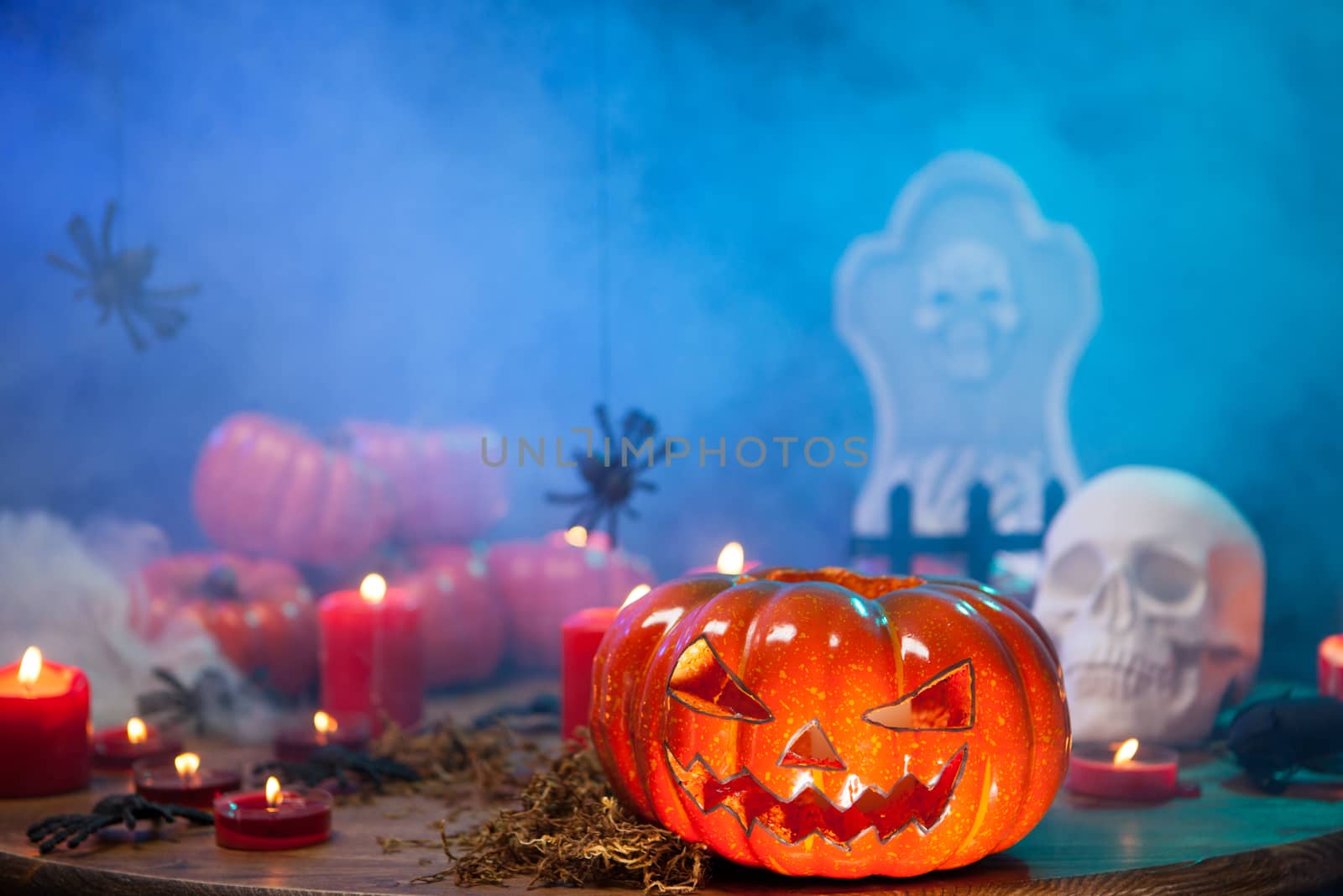 Burning candles at halloween celebration wtih creepy pumpkin near. Mysterious mist.