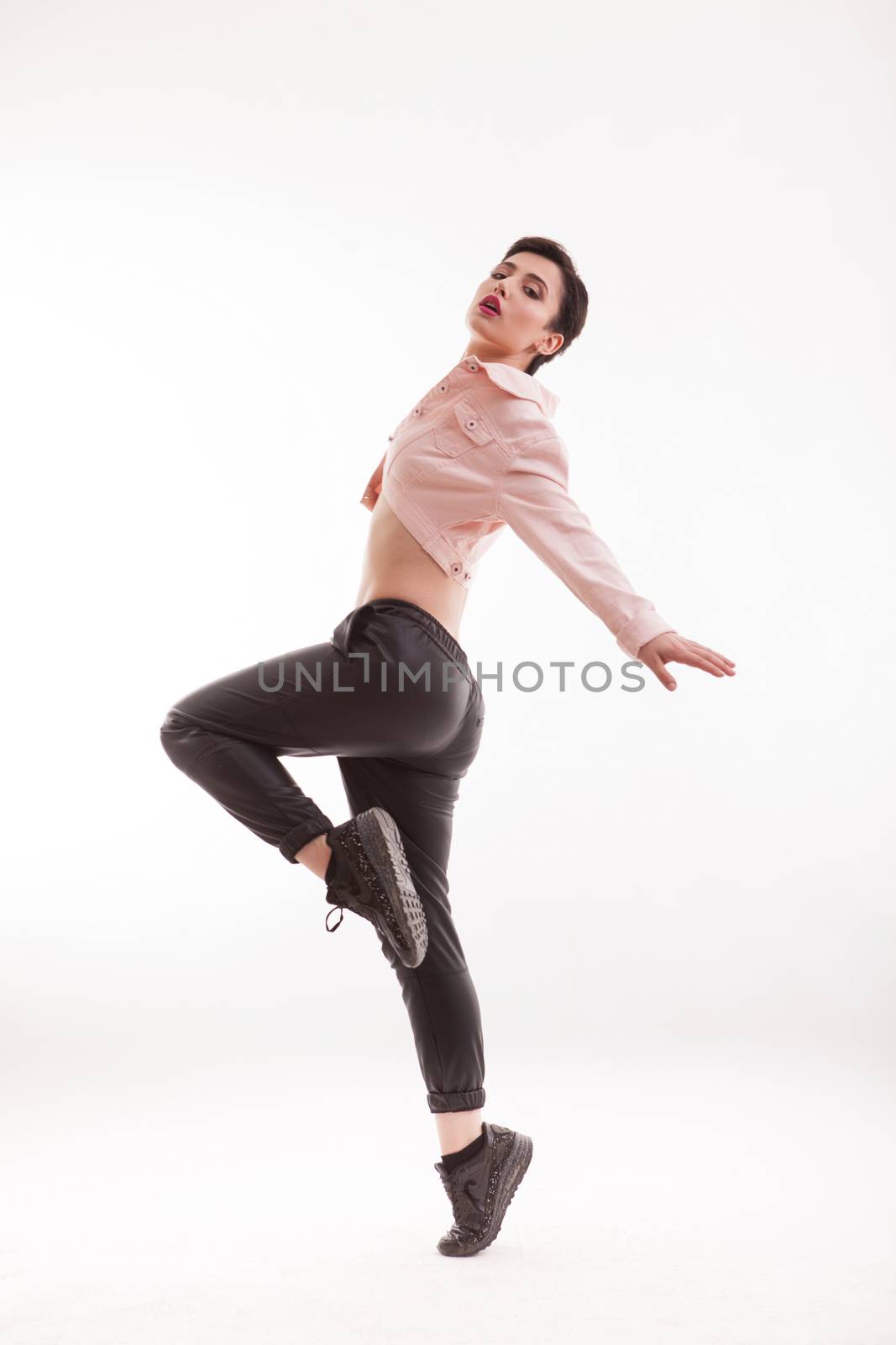Caucasian fashion model posing with confidence in front of the camera over white background. Fashionable outfit.