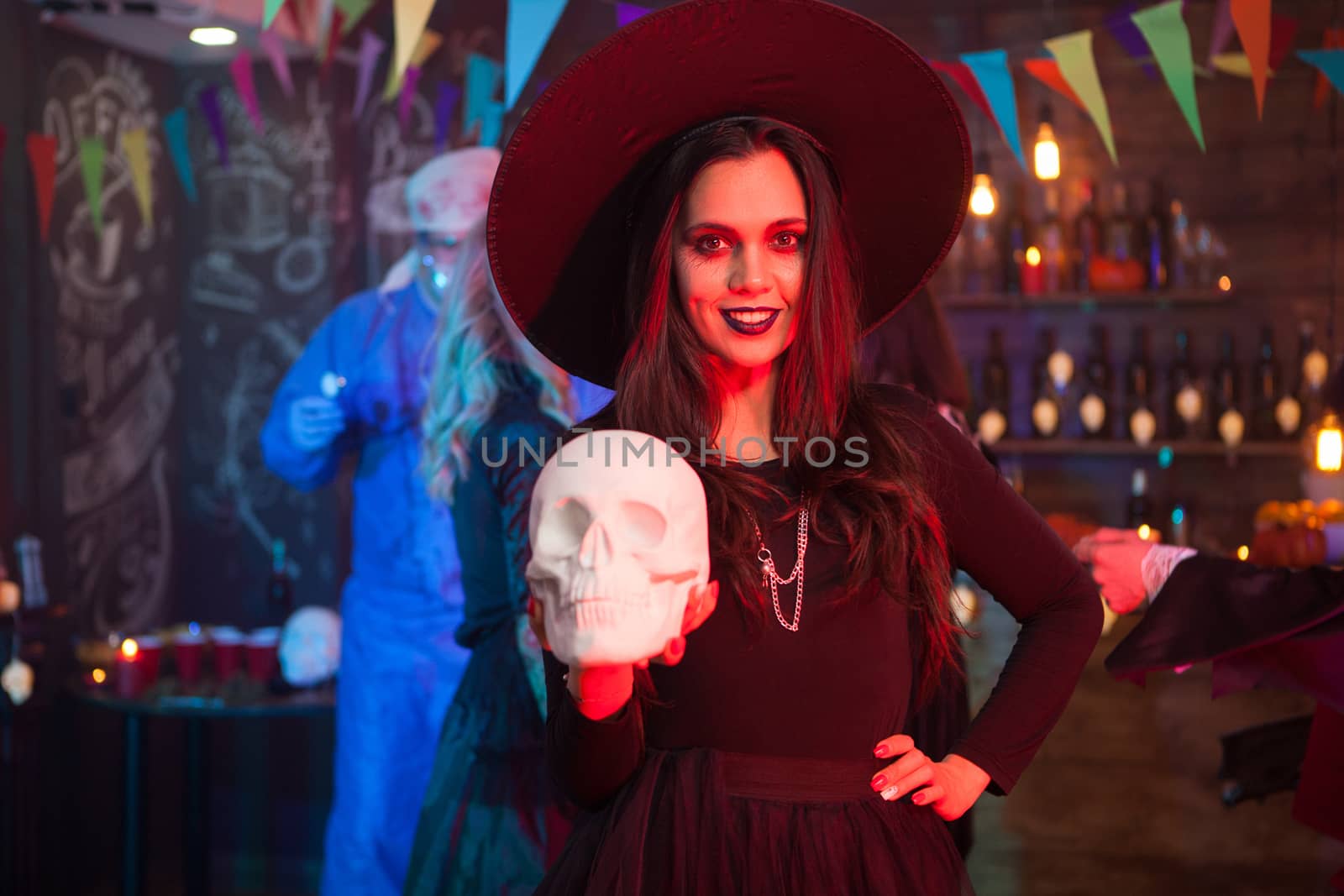 Beautiful young woman dressed up like a with for halloween with a magic hat on her head by DCStudio