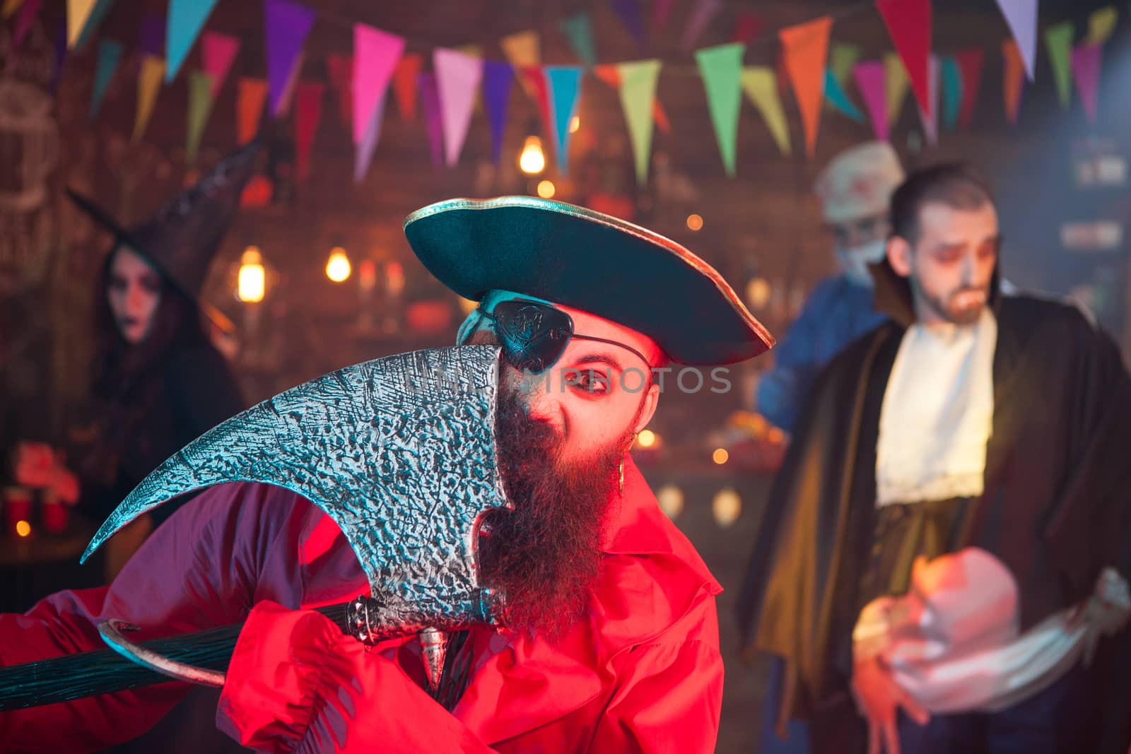 Portrait of one eyed pirate with axe celebrating halloween. Man dressed up like pirate.