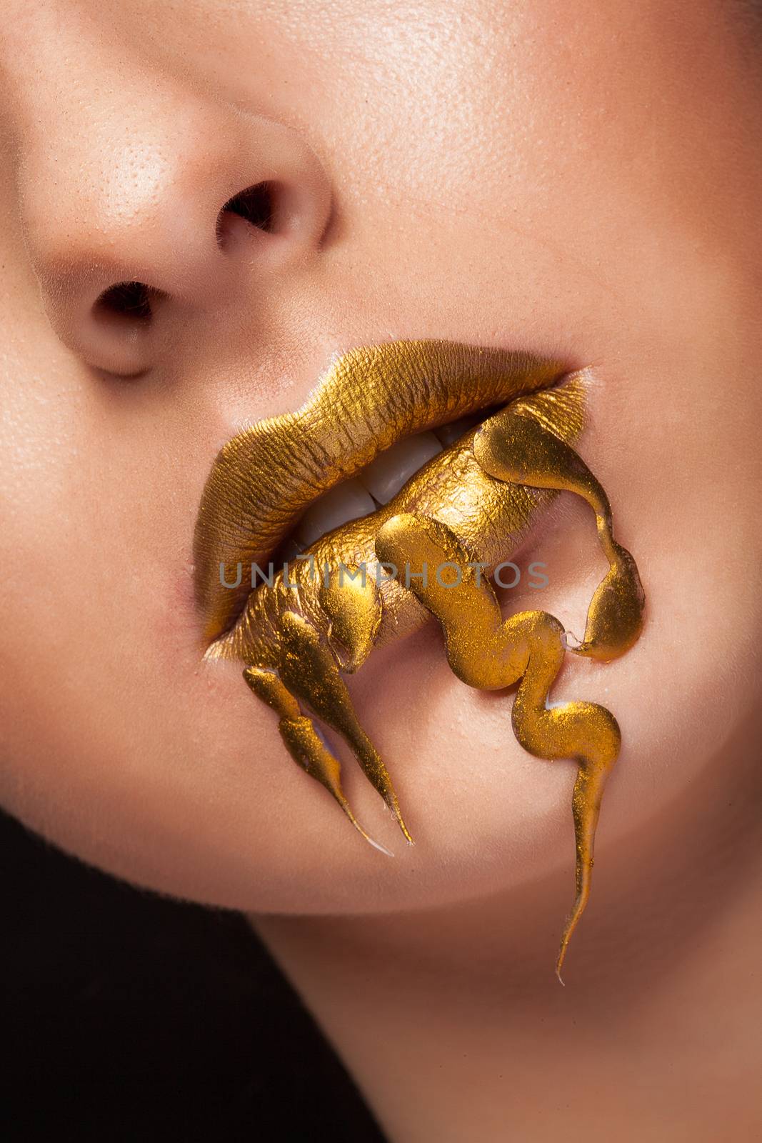 Close up golden lips of beauty model in studio. Open mouth. Shiny skin.