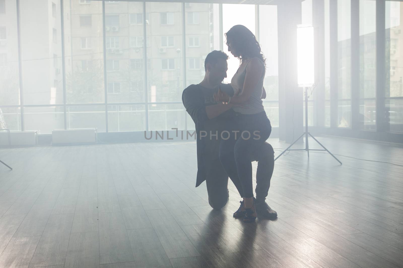 Active happy adults dancing kizomba in a dance room. Dancers silhouette. Skillful dancers.