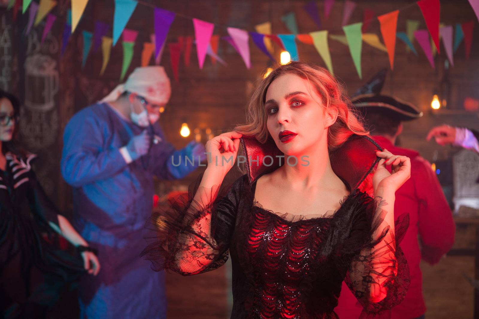 Portrait of sexy woman dressed up in a witch costume at halloween event. Scary doctor in the background.