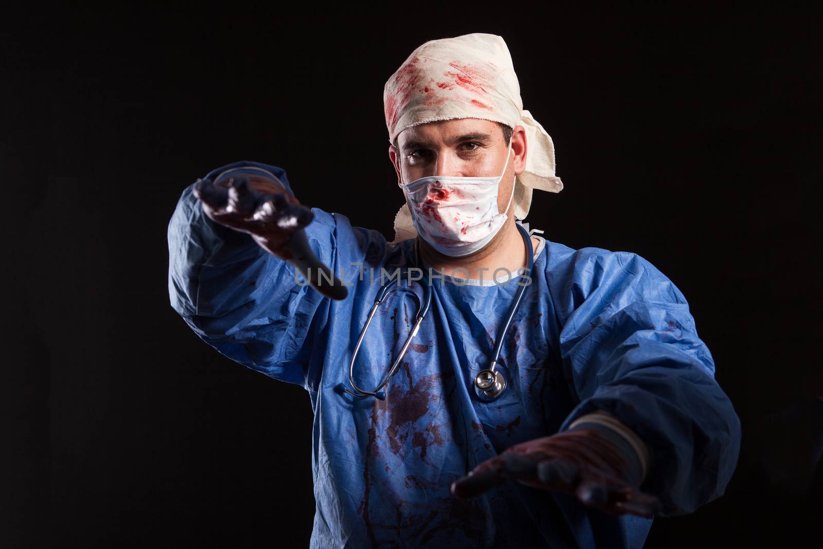 Portrait young man in crazy doctor clothes reaching out with his hands over black background for halloween carnival. Frustrated doctor with sinister look.