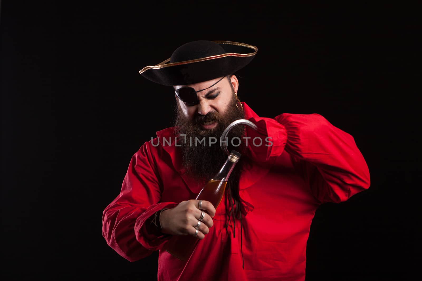 Man dressed up like a pirate for halloween opening a bottle with his hook. Man with a pirate hat. Man in pirate clothes.