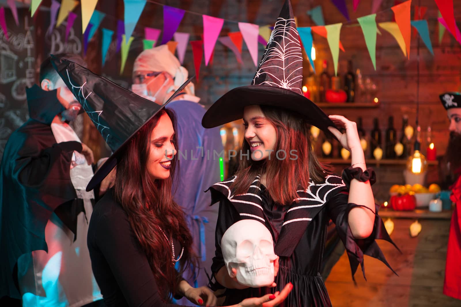 Beautiful witches looking at eachother at halloween celebration. Cheerful witches.