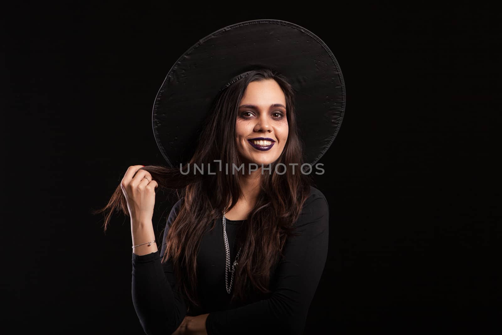 Cheerful beautiful woman in a witch costume with scary make up for halloween. Girl in black dress for halloween.