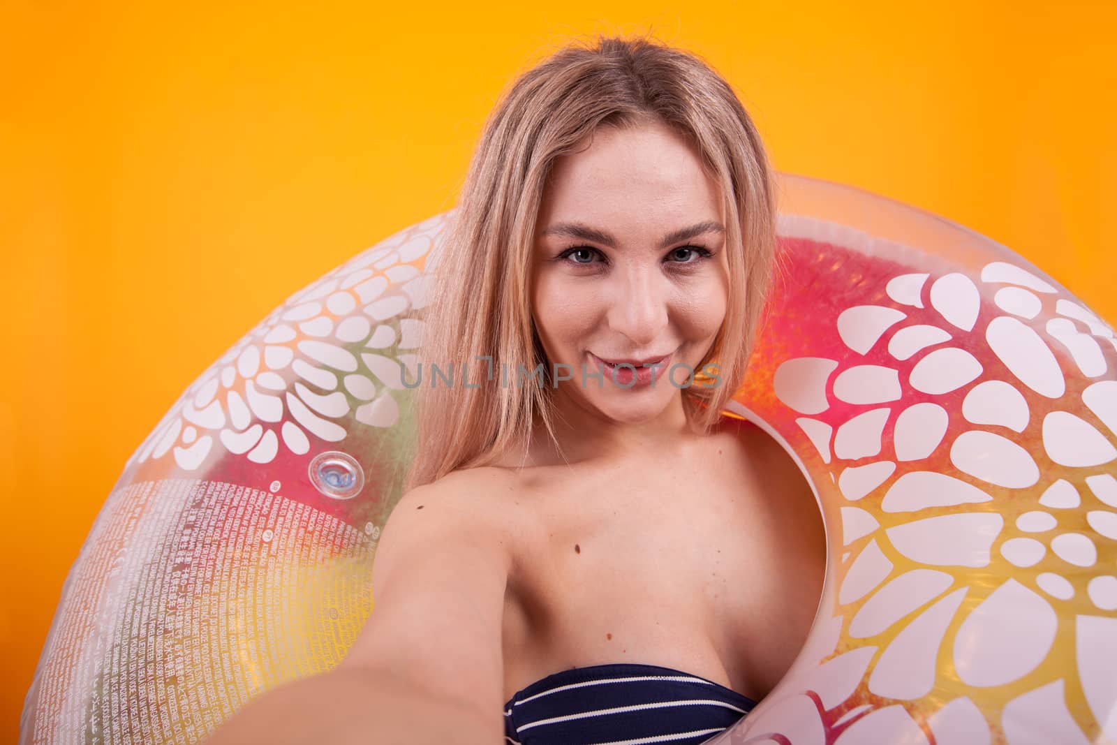 Gorgeous girl taking a selfie while she's through a swimming ring. Girl ready for summer vacation. Sexy young woman.