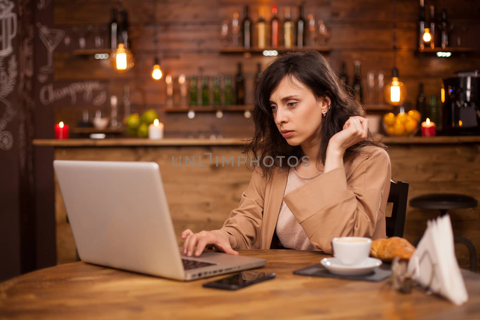 Portrait of beautiful business woman concentranting on her work in a coffee shop. Beautiful woman using her laptop in a coffee shopt with wireless internet. Cup of coffee. Smart entrepreneur in a hipster coffee shop.