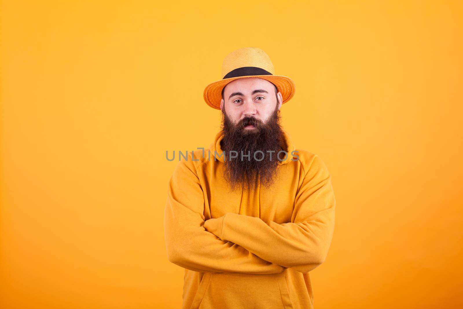 Hipster with long beard wearing an orange hat over yellow background. Coold man. Stylish man. Handsome man.