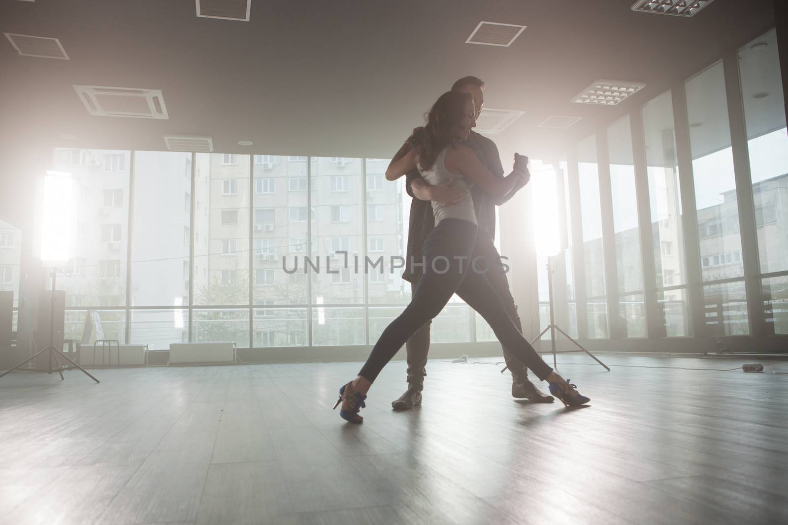 Kizomba dancers showing their passion for dancing kizomba in front a dancing room with big windows in the background. Passionate dancers.