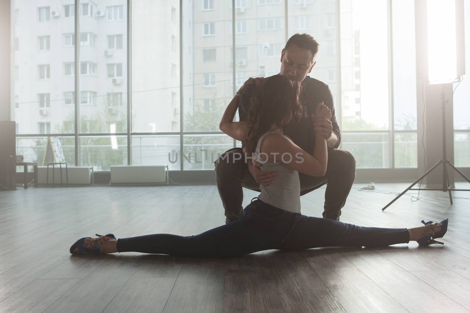 Male dancer looking at his partner while she's doing a slip in practice room. Graceful lady dancer.