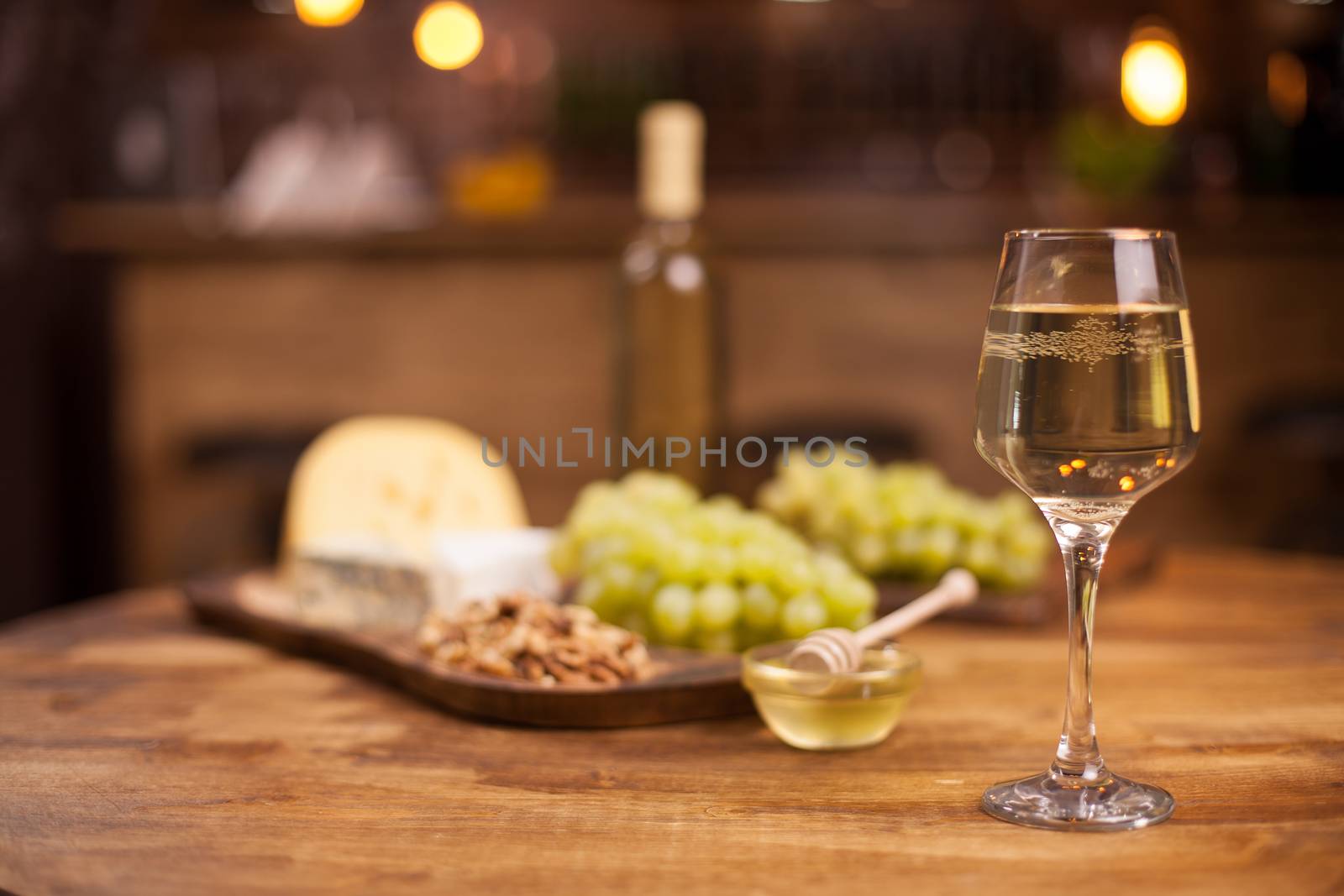 Glass of white wine with super consisting french cheese next to walnuts on rustic wooden table. Food tasting. Fresh grapes.