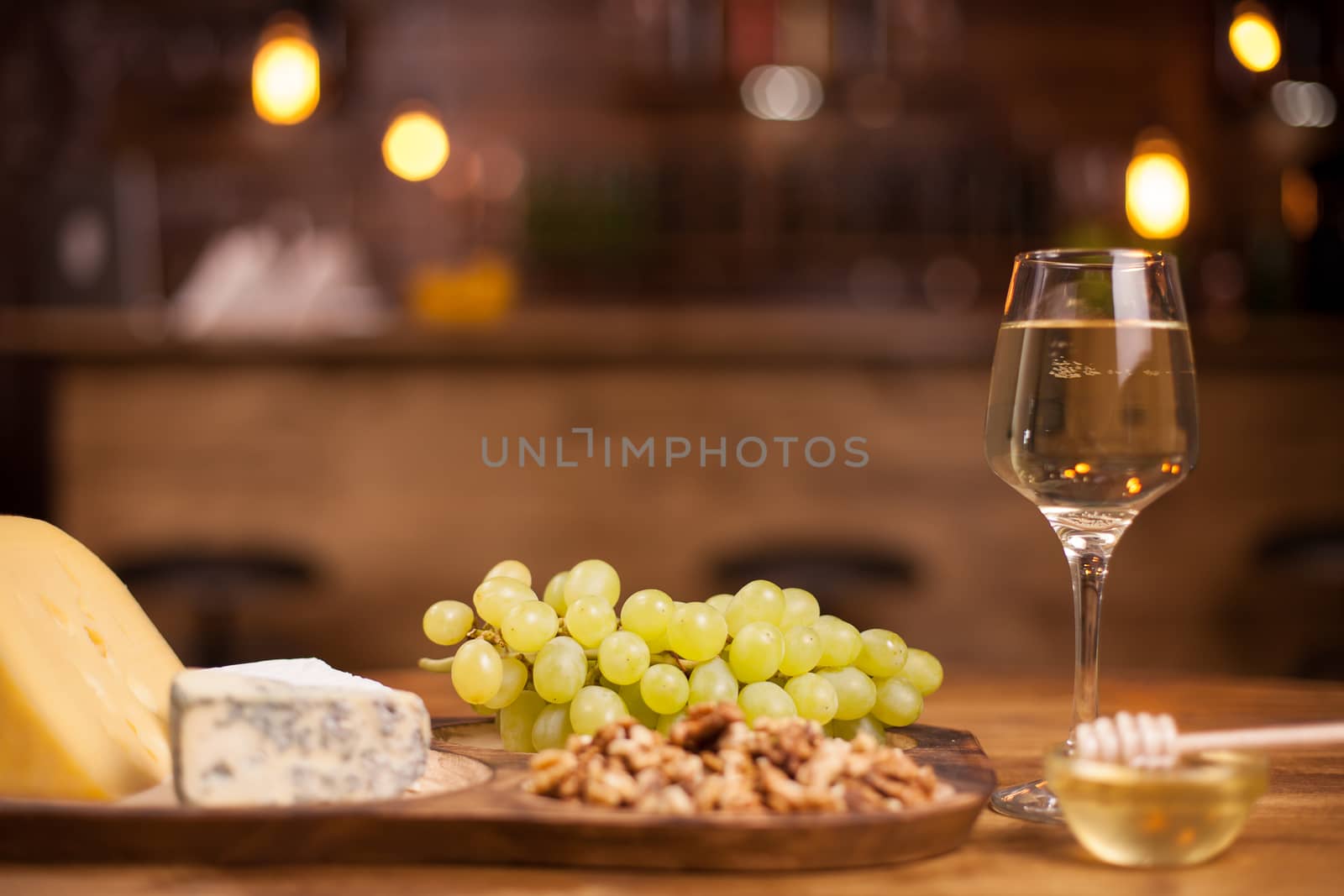 Photo of fresh grapes next to a wineglass on a wooden table. French cheese degustation. Tasty walnuts.