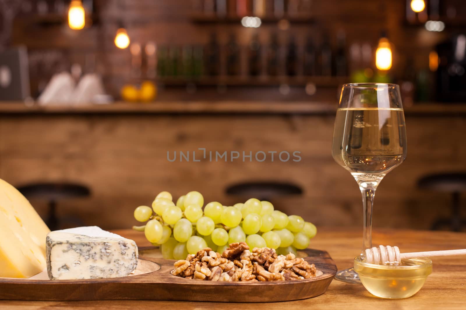 Food composition with varisious snacks for white wine on a wooden table. Fresh grapes. Walnuts on rustic plate.