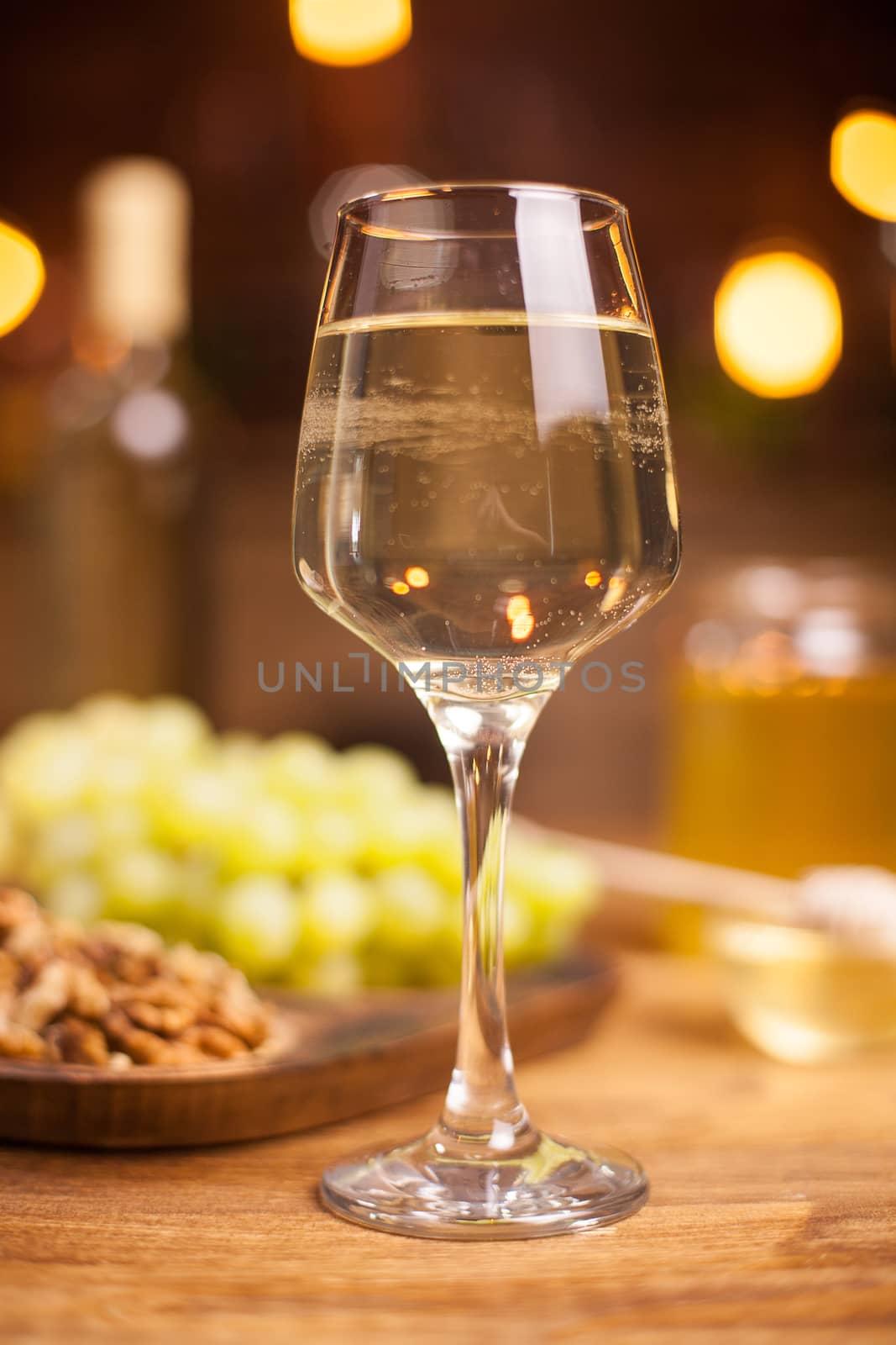 Close up photo of a glass of white wine on a wooden table. Delicious grapes. Tasty walnuts.