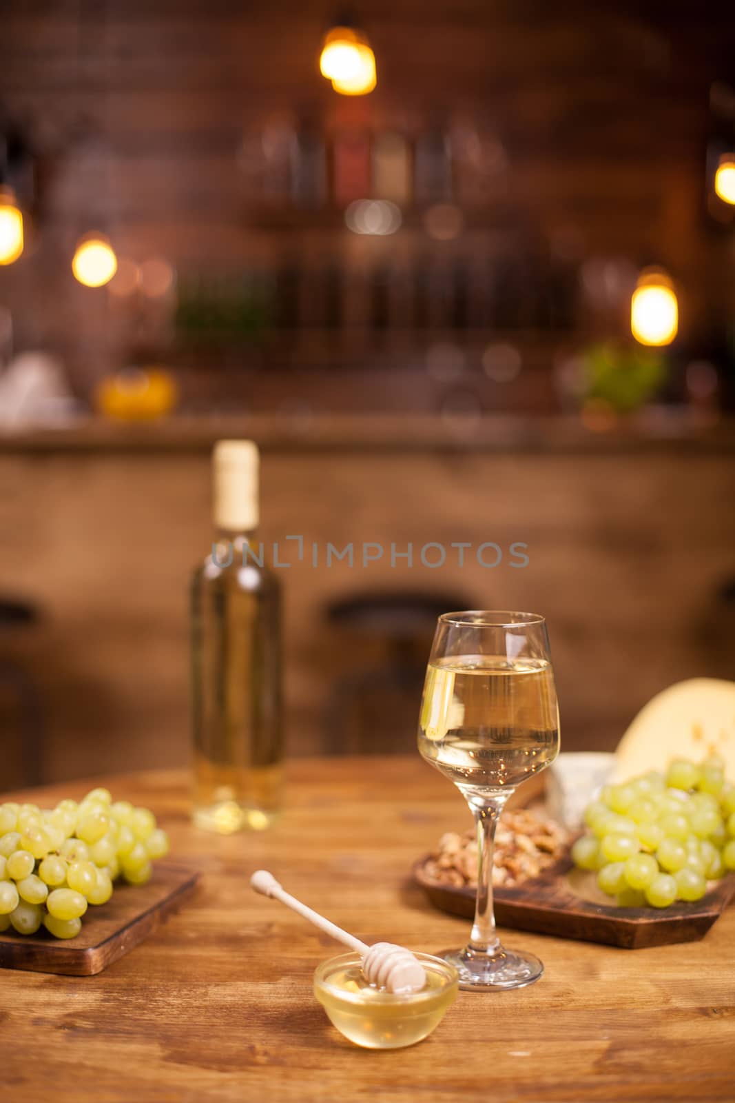 Cheese plate served with a glass of white and wolnuts in a vintage restaurant over a wooden table. Fresh natural grapes.