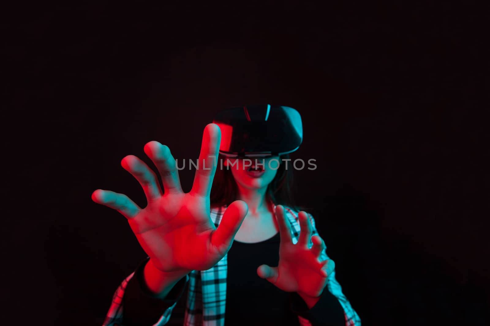 Portrait of surprised young girl using modern virtual reality headset in studio. Joyful teenage girl with virtual reality goggles.
