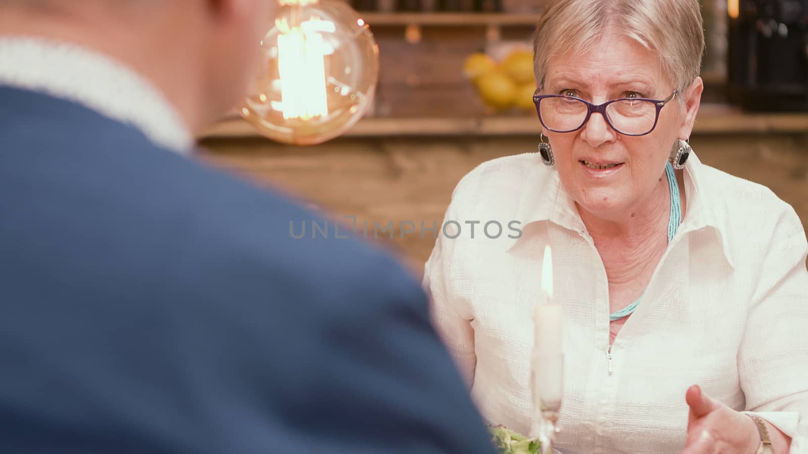 Woman in her sixties telling her husband an interesting story during mealtime in a restaurant. Couple talking. Relaxed couple. Two pensioners.