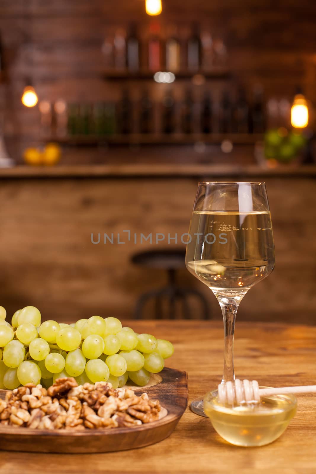 Glass of white wine with fresh grapes and wolnuts on a wooden plate in a vintage restaurant. French wine. Wine celebration.