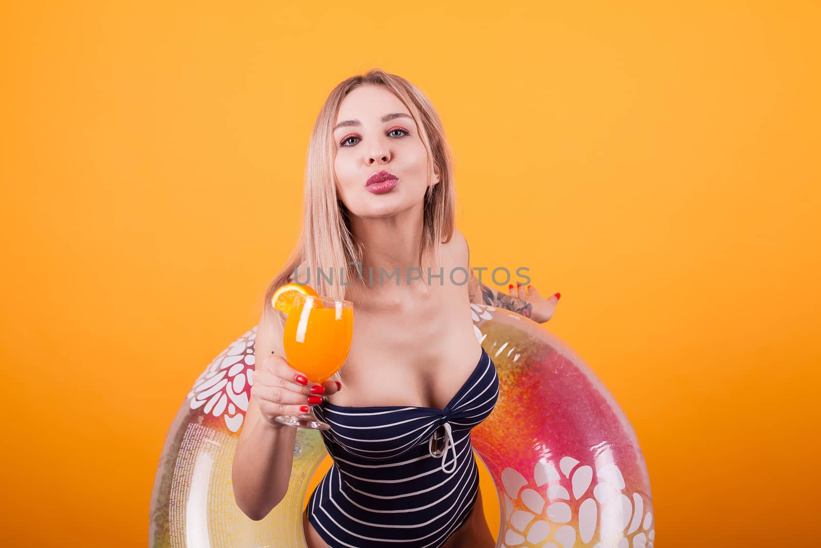 Attractive young woman giving a kiss to the camera over yellow background. Beautiful woman. Summer vibe.