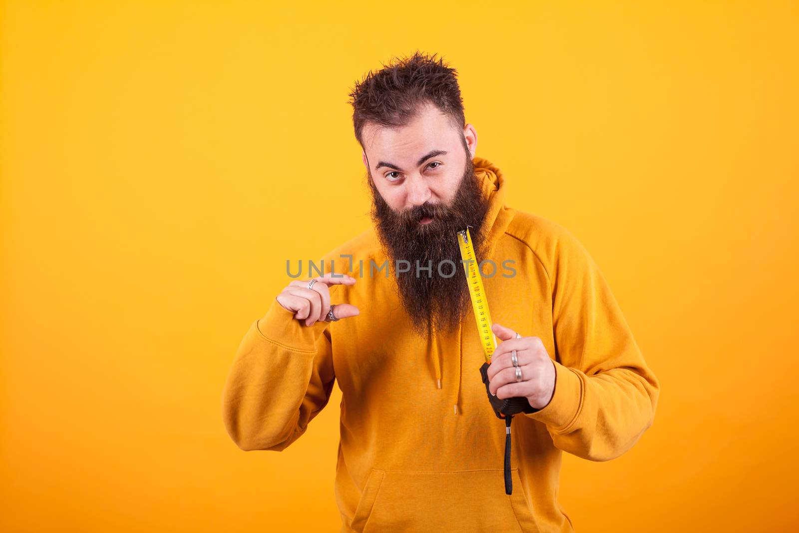 Funny bearded man showing dimension on roulette over yellow background.Handyman. Constructor