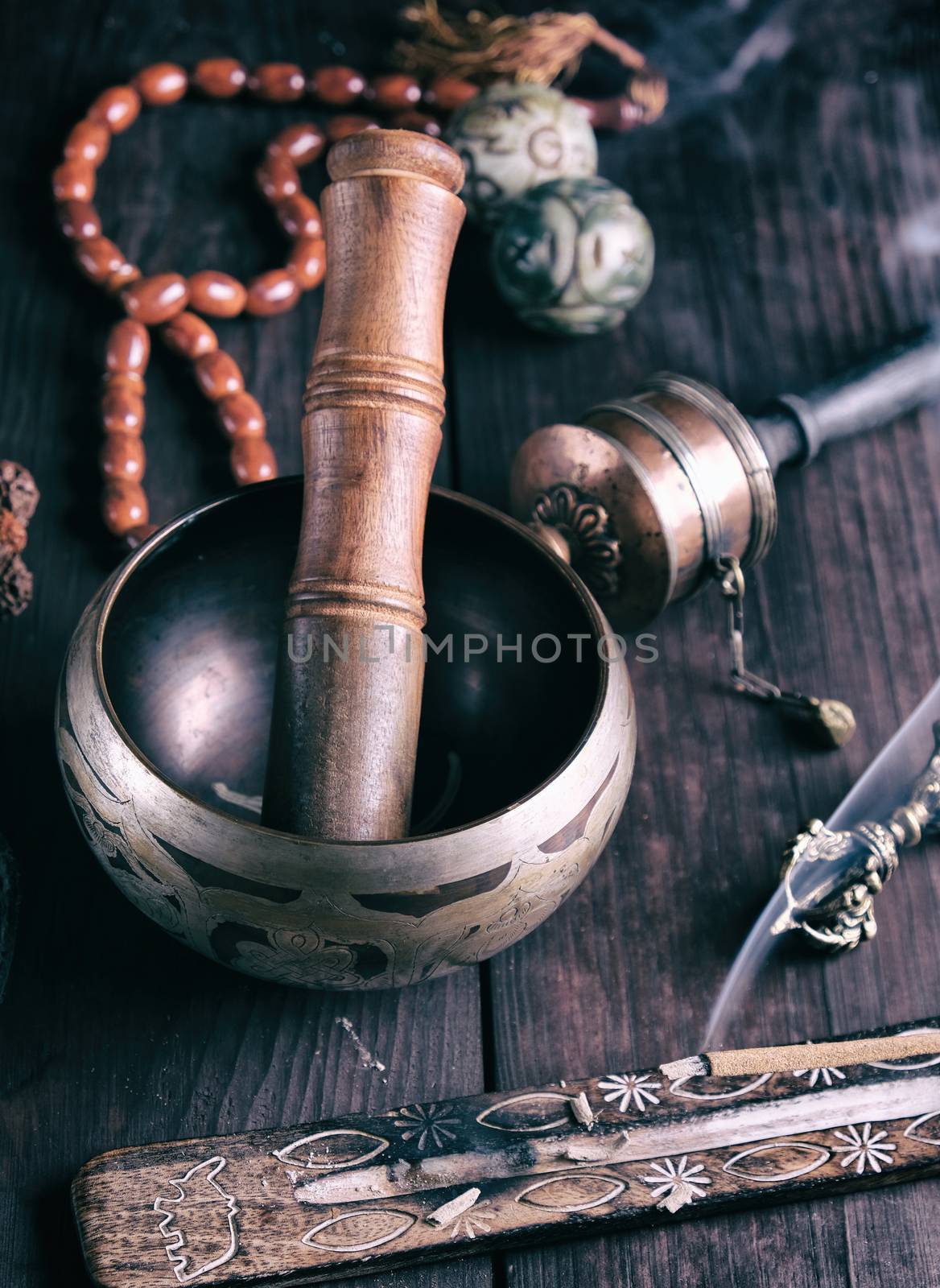 copper singing bowl and a wooden stick on a brown table, vintage toning