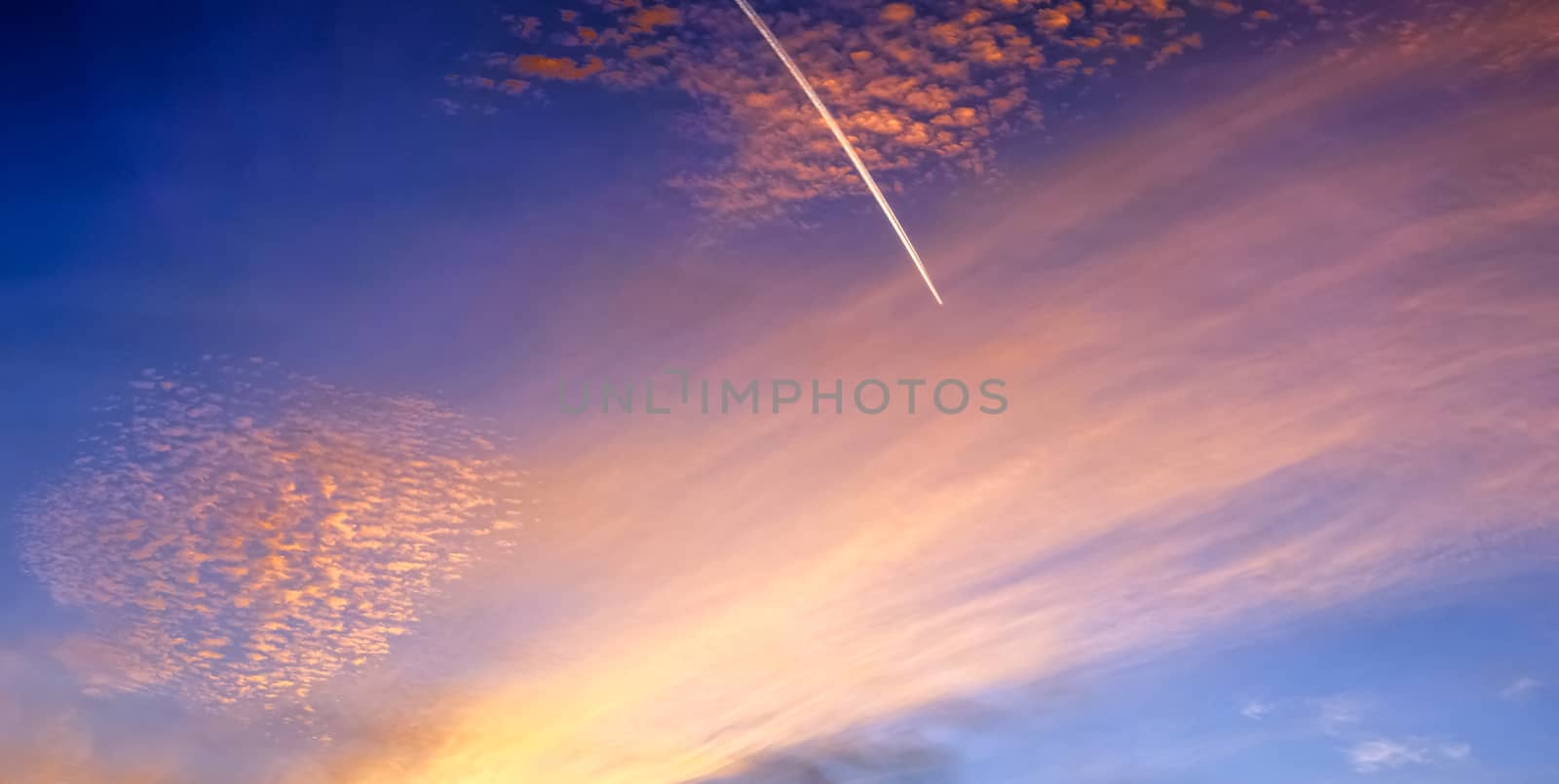 Beautiful high resolution panorama of orange and red sunset clouds in the evening sky.