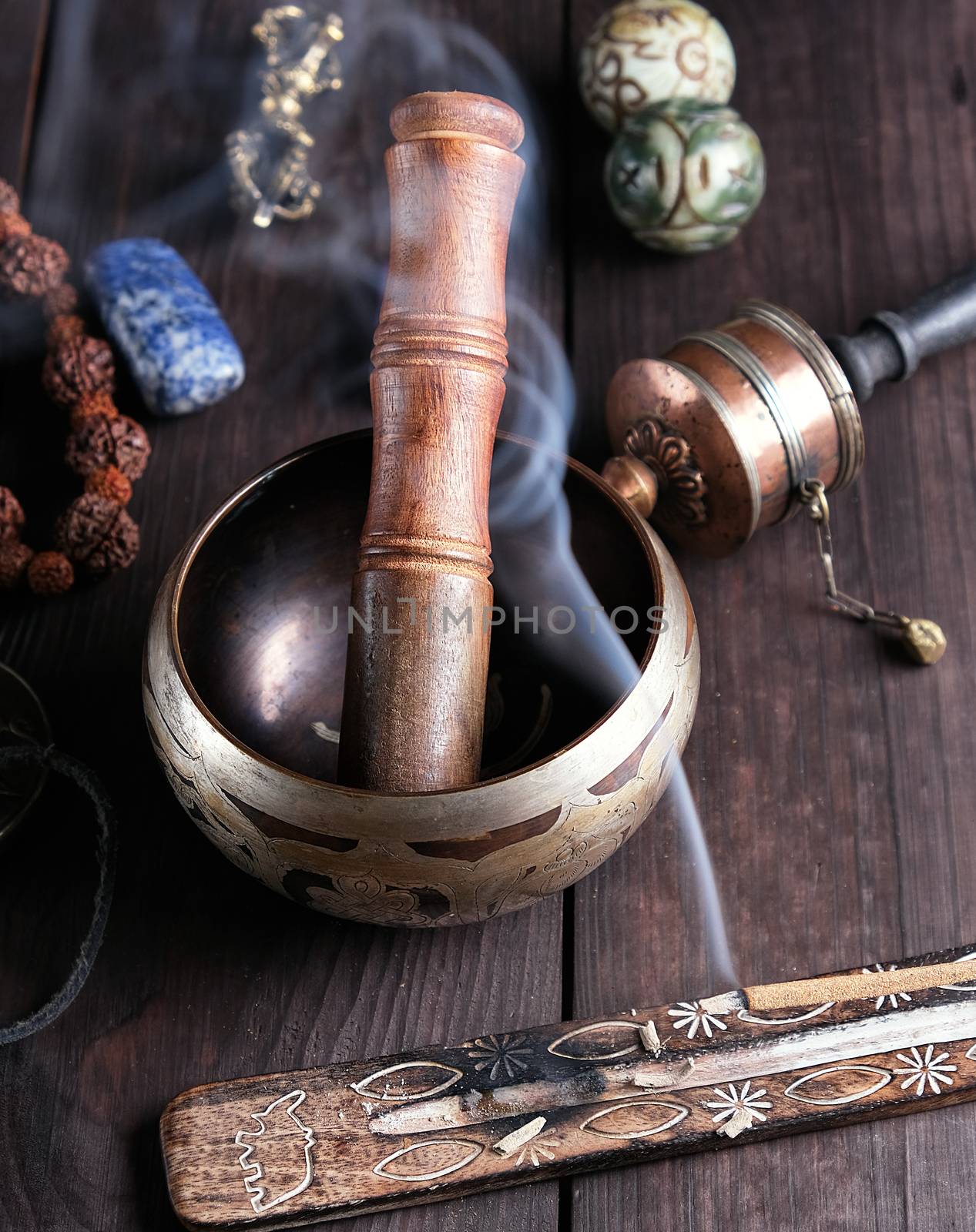 copper singing bowl and a wooden stick on a brown table