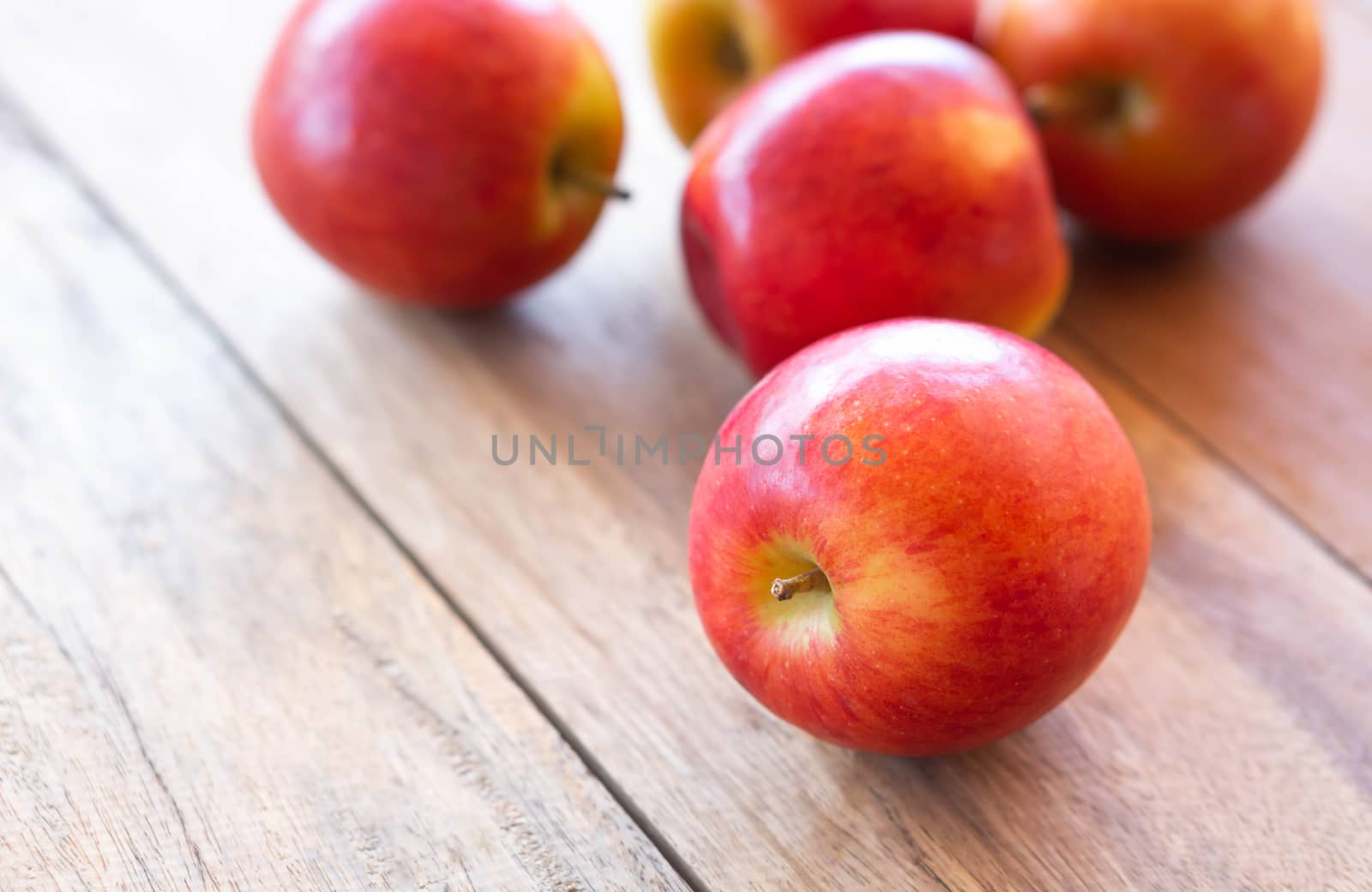 Closeup fresh red apples fruit on wood table background with light from out door, food healthy diet concept