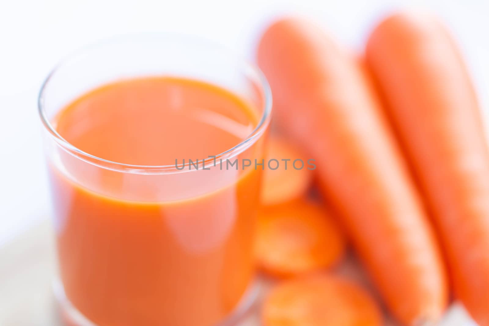 Closeup top view glass of carrot juice and fresh carrot with over light, selective focus