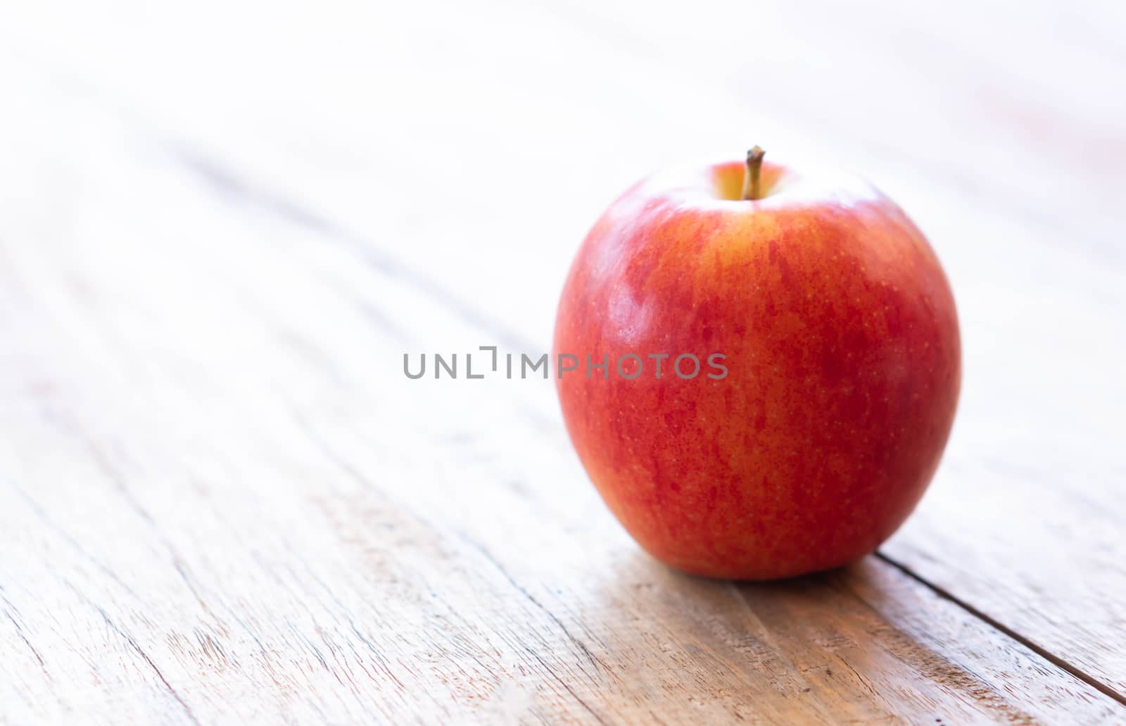 Closeup fresh red apple fruit on wood table background with light from out door, food healthy diet concept