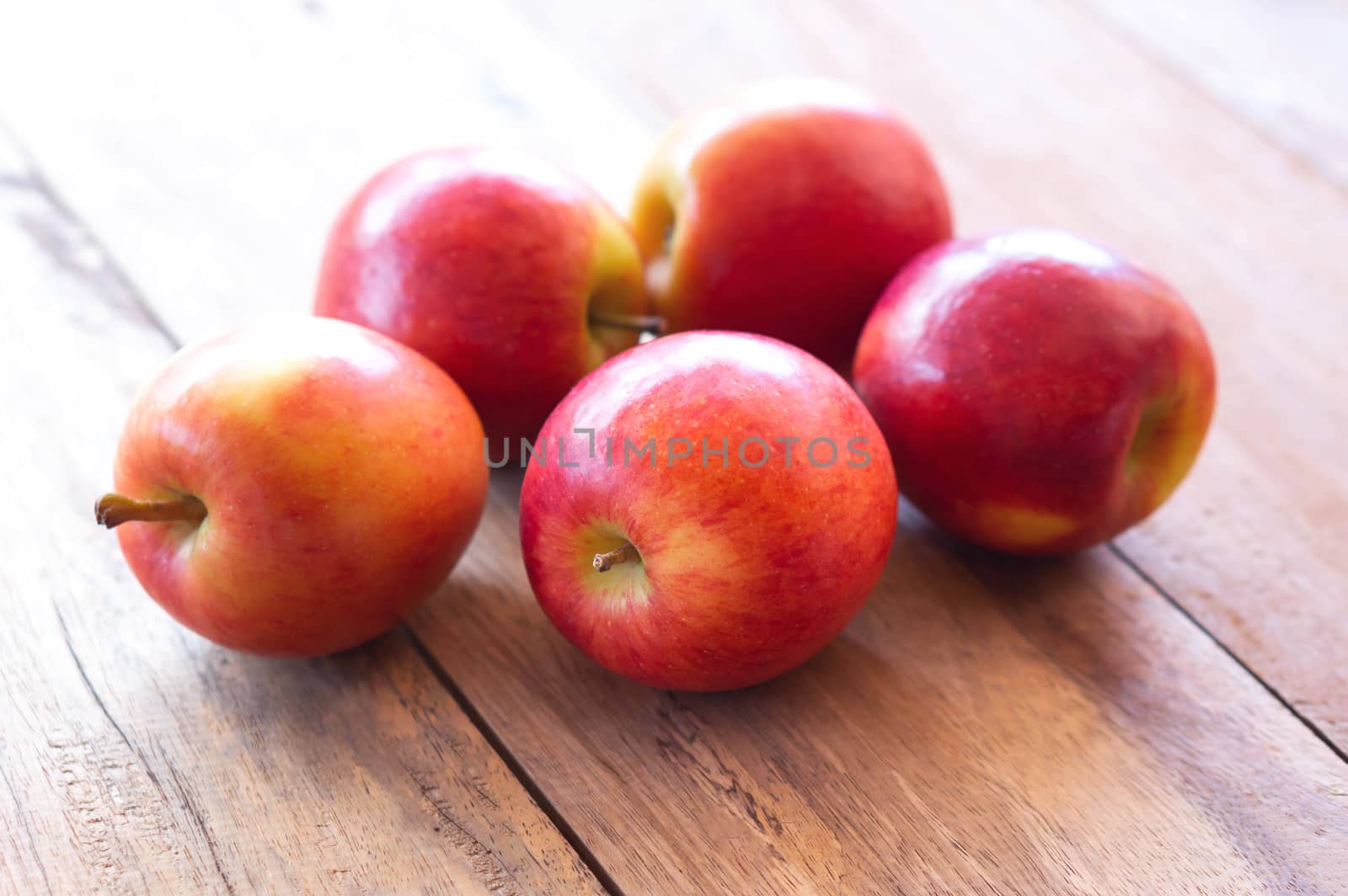 Closeup fresh red apples fruit on wood table background with light from out door, food healthy diet concept