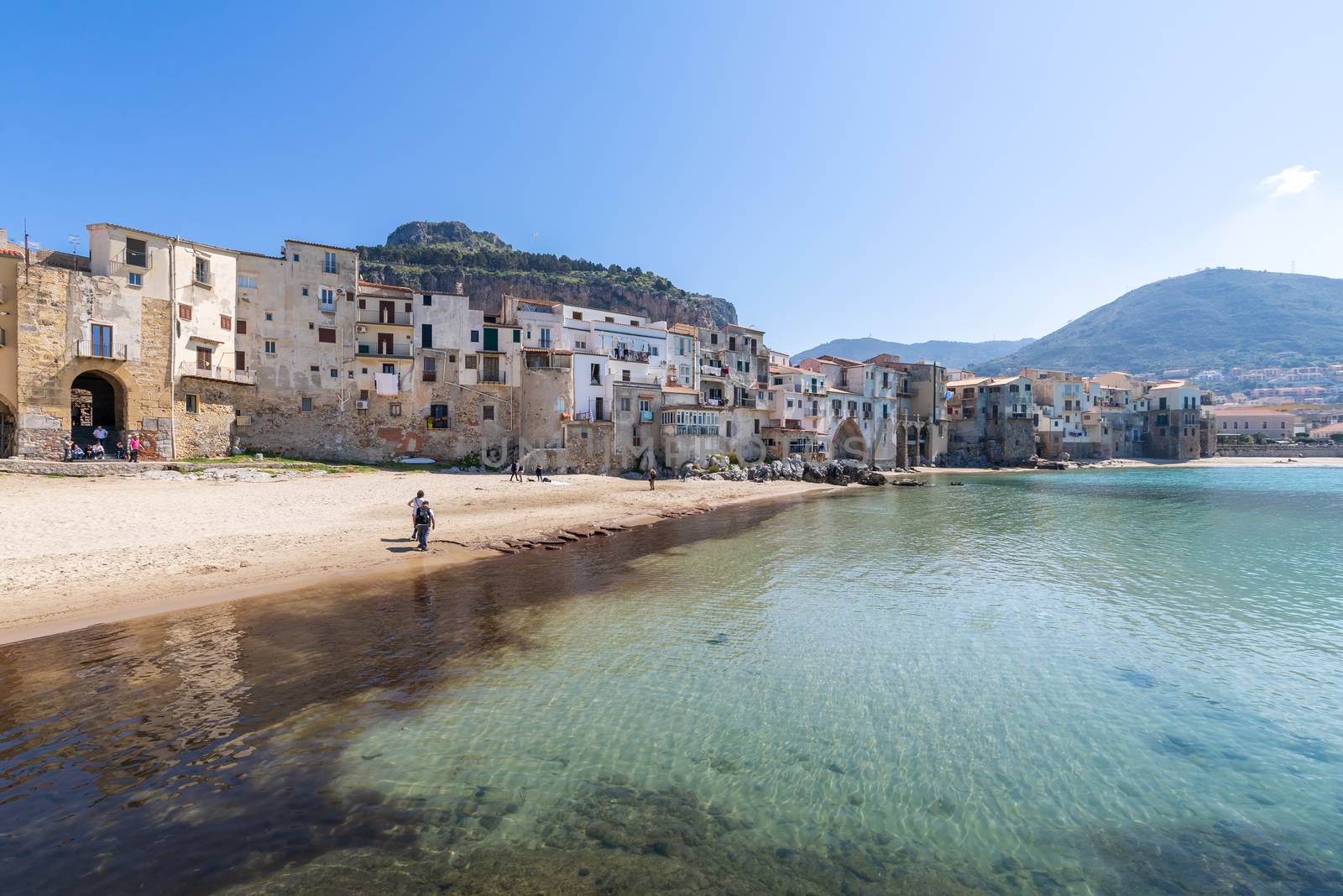 Idyllic view of turquoise sea and houses with Rocca di Cefalu rocky mountain in the background seen from historical old harbour of Cefalu, Sicily, Italy. by tamas_gabor